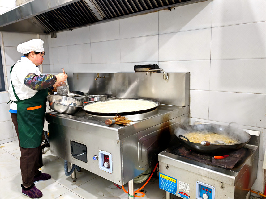 在岷山路社区长者食堂后厨，工作人员正忙着备菜、烹饪，为老人的午餐做精心准备。罗金摄