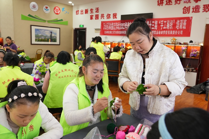 在丹都街道旺家社区微工厂手工传习基地，负责人许平正手把手地向学员传授毛线钩织技巧.jpg