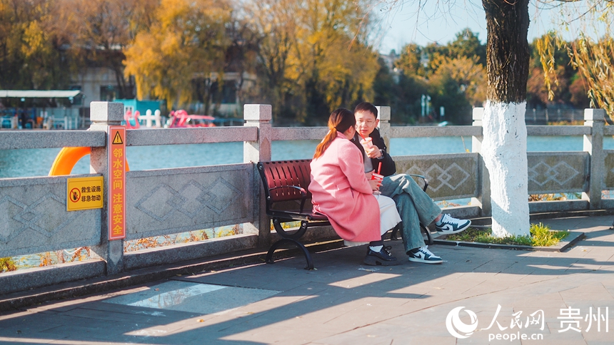 市民坐在公园内的长椅晒太阳。人民网记者 涂敏摄