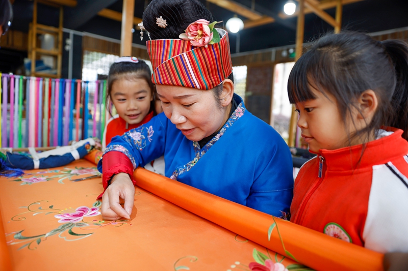 2025年12月10日，非遗代表性传承人在给贵州省黔东南苗族侗族自治州施秉县第四幼儿园的孩子们展示苗绣技艺。