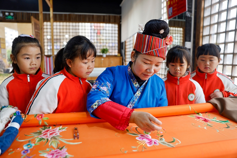 2025年12月10日，非遗代表性传承人在给贵州省黔东南苗族侗族自治州施秉县第四幼儿园的孩子们展示苗绣技艺。
