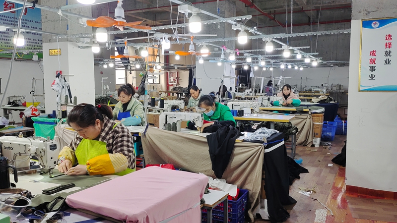 工人们正紧张有序地加工各式各样的服饰。