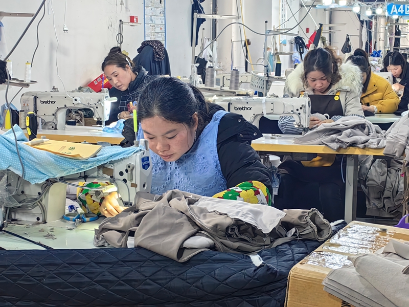 工人们正紧张有序地加工各式各样的服饰。