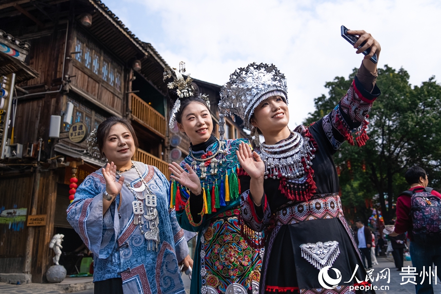 12月20日,身着盛装的少数民族同胞在肇兴侗寨内打卡拍照。人民网记者 涂敏摄