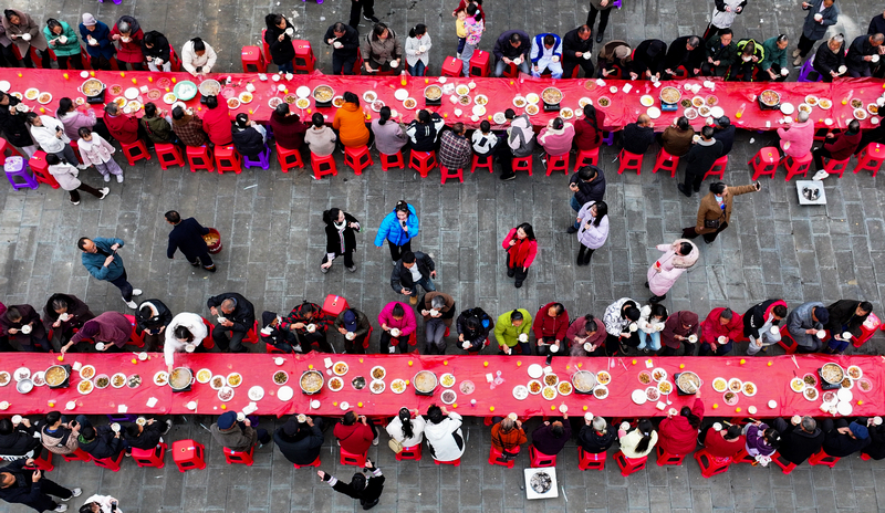 2025年12月21日，贵州省铜仁市玉屏侗族自治县新店镇大湾村，游客和村民在品尝长桌宴。