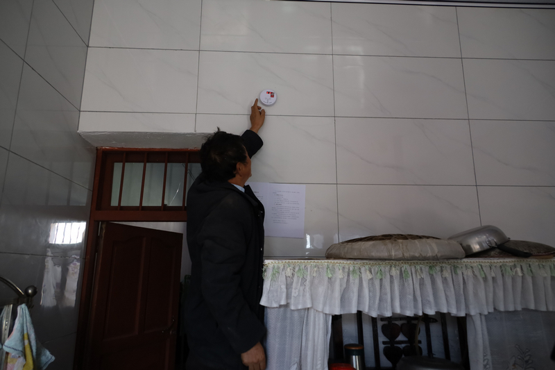 板底鄉曙光村群眾查看家裡的一氧化碳報警器。