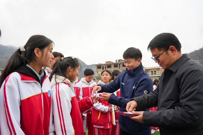 2025年12月24日，贵州省毕节市纳雍县化作中学，纳雍籍奥运冠军谢瑜在给同学们派发“小谢瑜”勋章。