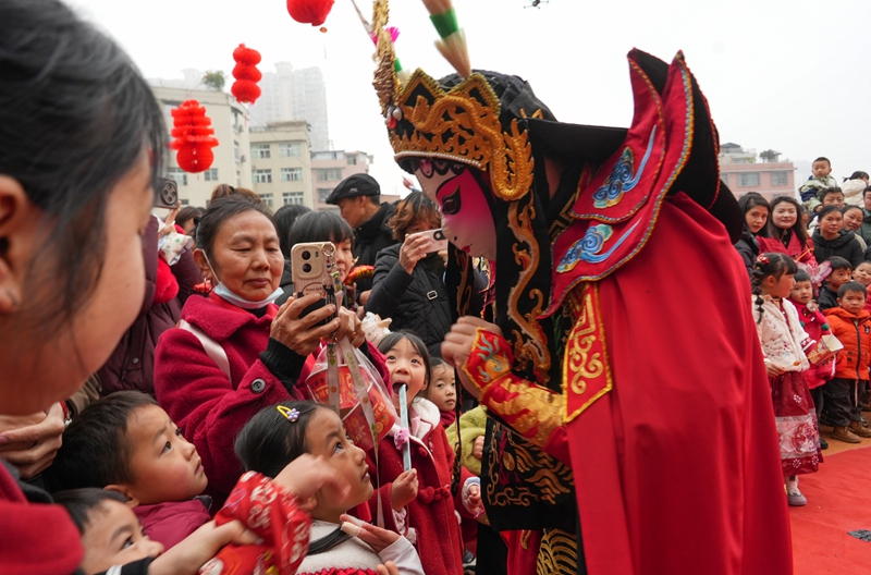 2025年12月31日，貴州省畢節市納雍縣廣黔同心幼兒園“童趣廟會”現場，川劇變臉表演都和小朋友們互動 。 楊英 攝