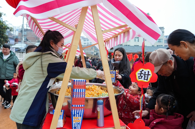 2025年12月31日，貴州省畢節市納雍縣廣黔同心幼兒園“童趣廟會”現場，小朋友在買爆米花。 楊英 攝