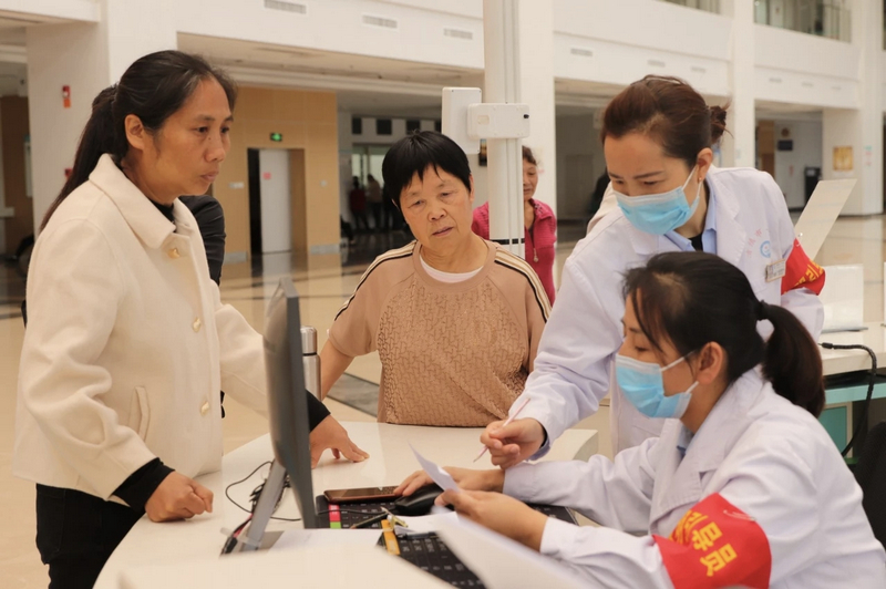 清镇市第一人民医院内，引导员在向患者家属讲解就医程序。