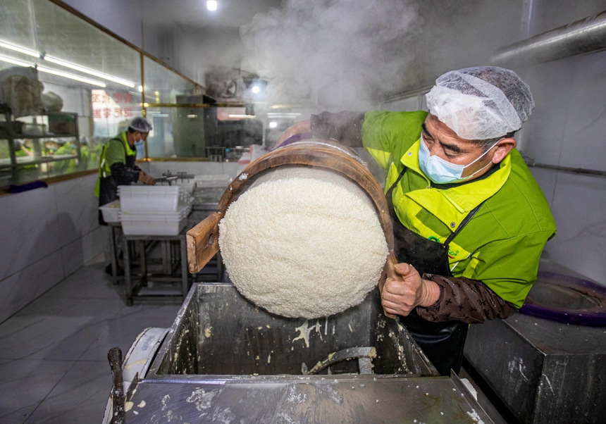 2026年1月11日，在貴州省黔西市錦繡街道金鳳社區一家食品企業，工人把蒸熟的糯米等原料進行攪拌。_T9A3278