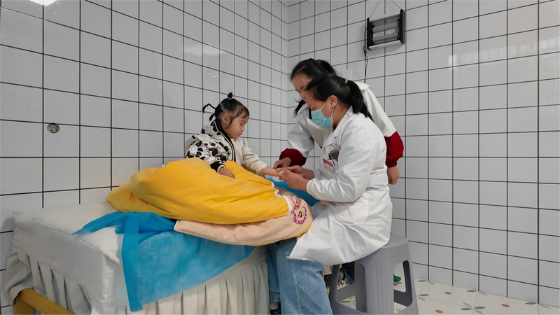 天柱县妇幼保健院儿科执业医师陈媛在托育中心为小朋友做小儿推拿。