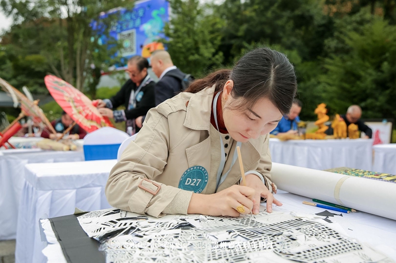 6、江露莎在活动现场精细勾勒剪纸纹样。习水县融媒体中心供图