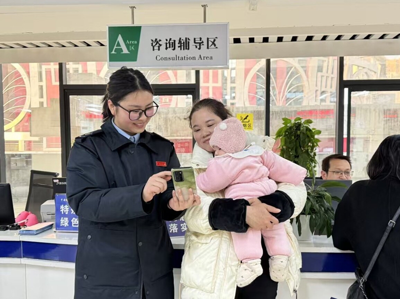 税务干部“一对一”辅导缴费人使用手机APP缴纳社保费。