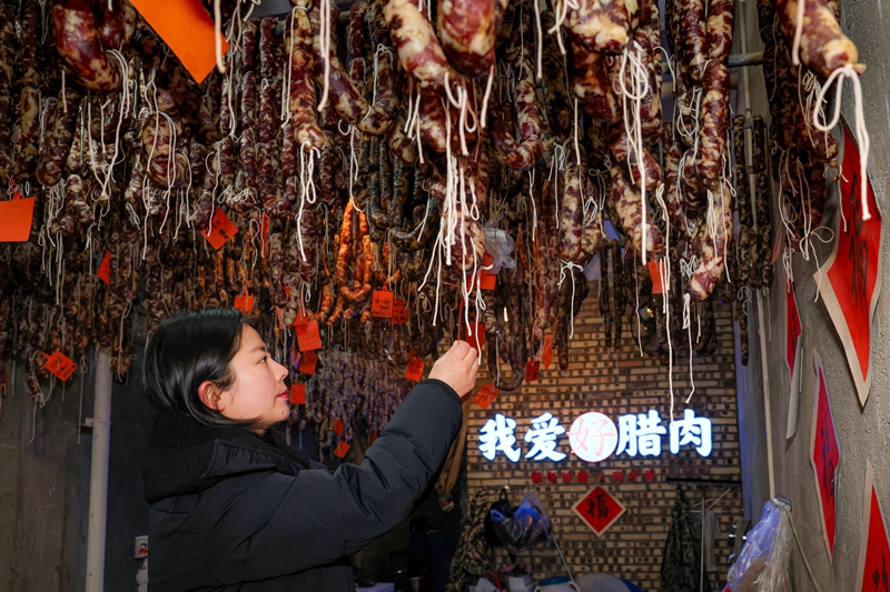 2026年1月26日，贵州省毕节市七星关区锄禾农特产品店工人给顾客定制的香肠悬挂标签。