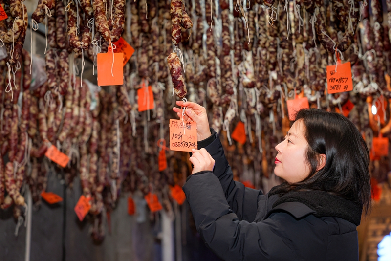 2026年1月26日，貴州省畢節市七星關區鋤禾農特產品店工人給顧客定制的香腸懸挂標簽。