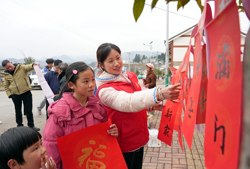 2026年1月26日，贵州省毕节市纳雍县张家湾镇普洒社区，大学生志愿者和小朋友一起挑选春联。