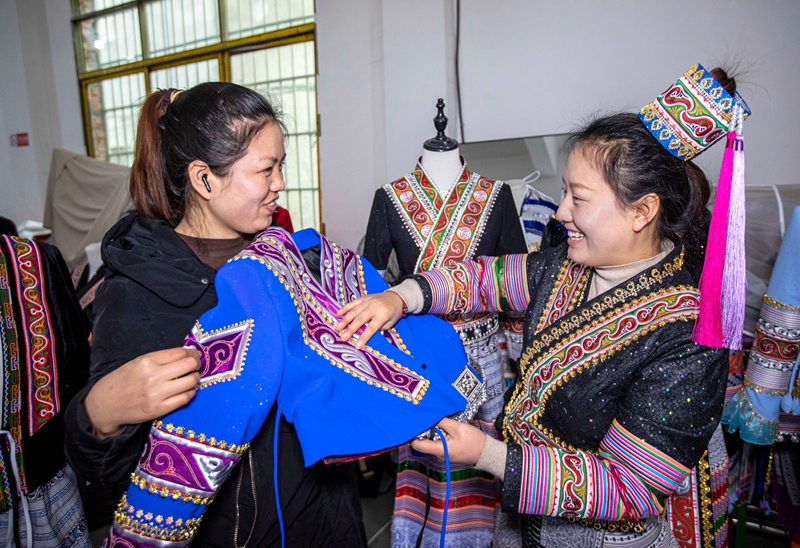 在黔西市林泉镇高锦社区一家苗族服饰加工车间，顾客（左）在选购苗族服饰。