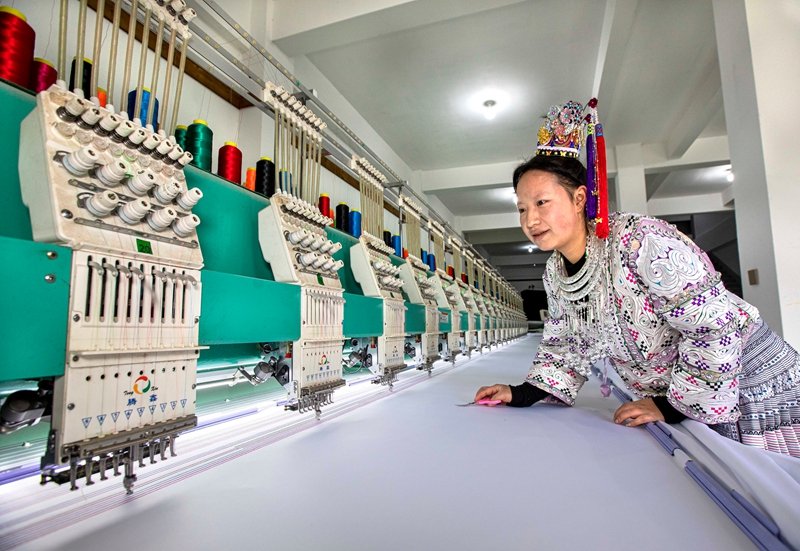 在黔西市林泉镇高锦社区一家苗族服饰加工车间，村民在电脑绣花机上作业。
