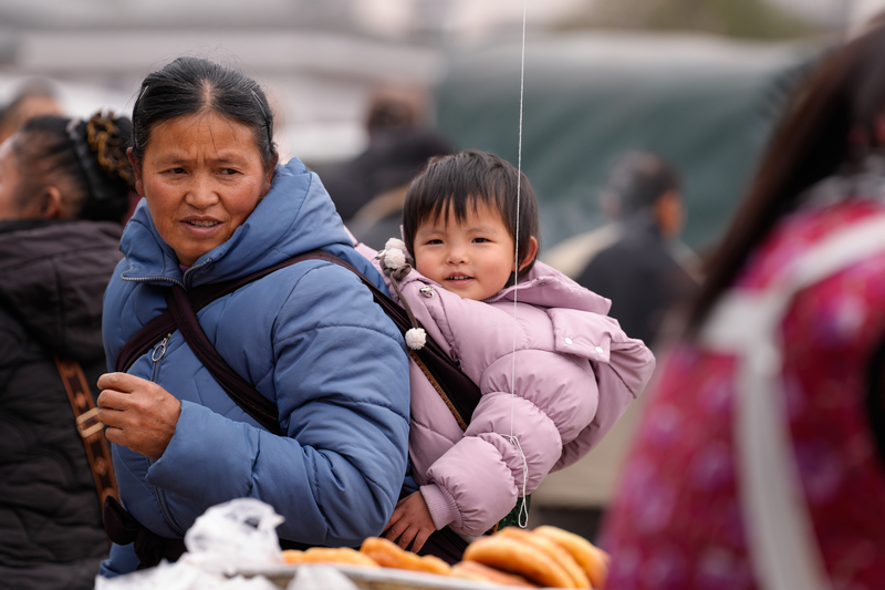 1月23日，凱裡下司大集，開心地和奶奶一起逛大集的小女孩。