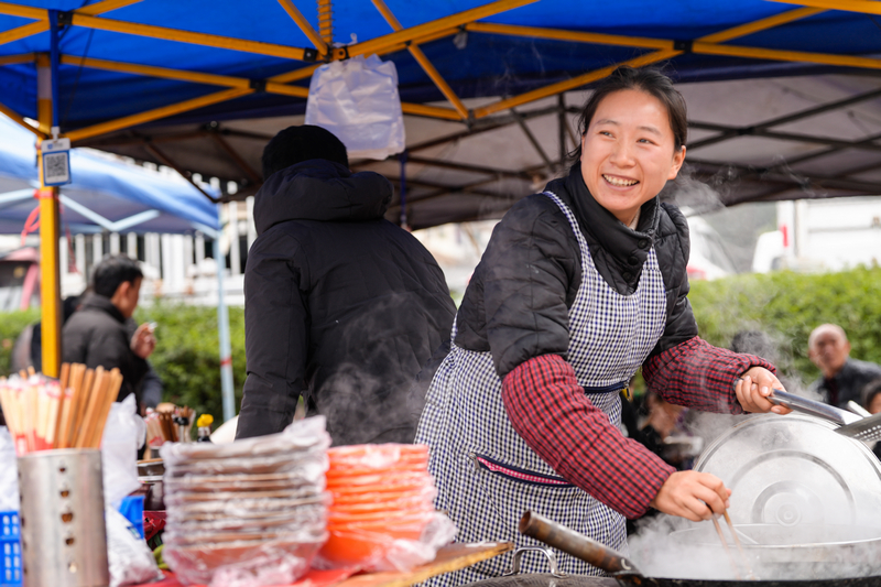 1月23日，凱裡下司大集上粉攤老板娘看著生意來樂了。