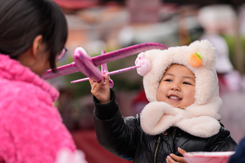 1月23日，凱裡下司大集上小朋友開心地玩著媽媽給買的玩具。