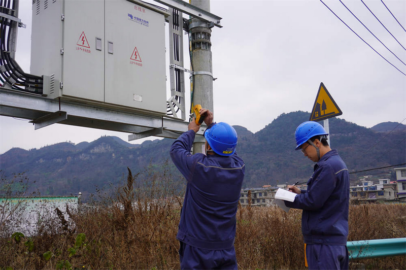 工作人员正对村寨中的配变进行巡视测温。