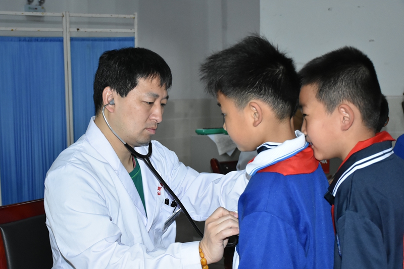 东莞帮扶专家王智明在筛查现场为孩子们做检查.jpg