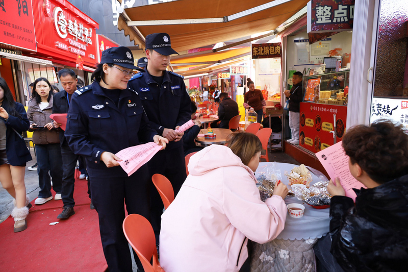 工作人員在會展中心附近檢查小吃攤點食品安全並向顧客發放宣傳資料。