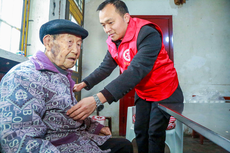 貴州省遵義市播州區龍坑街道八裡社區黨員干部為102歲淳祖開老人拉家常，幫助老人整理衣服。