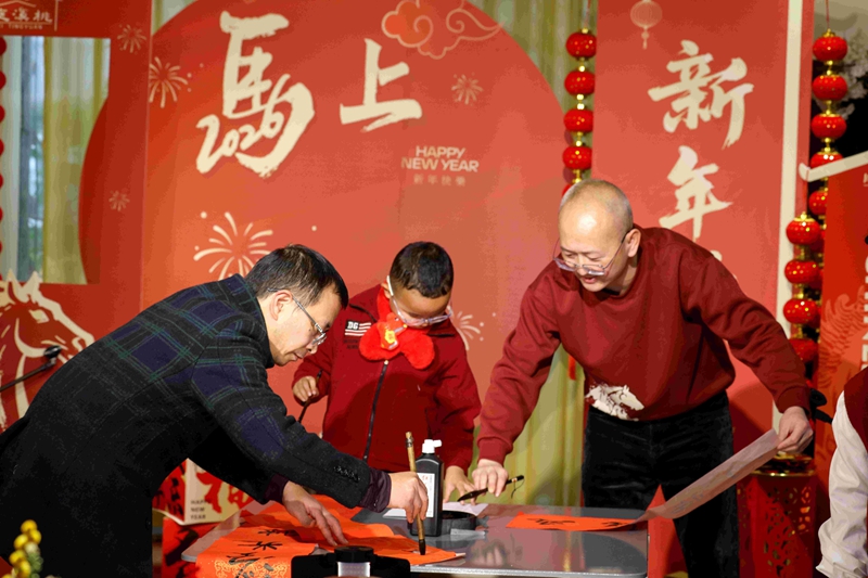 2月12日,家人在贵州省遵义市红花岗区忠庄街道桃溪庭院家庭春晚上现场写春联。李仁军摄