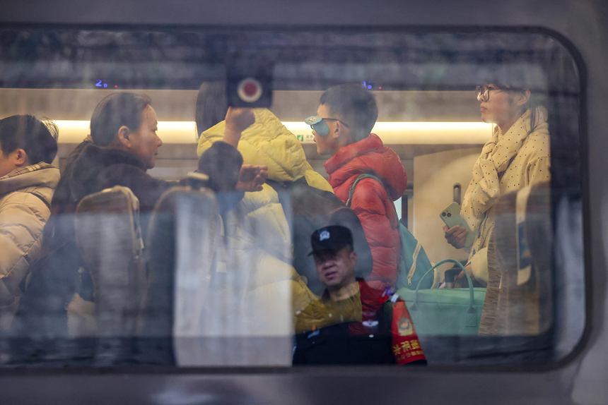 铁路公安民警在观察帮助过的旅客进入列车寻找座位。