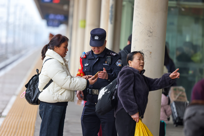 鐵路公安民警在幫助旅客查找所乘坐的列車座位信息。