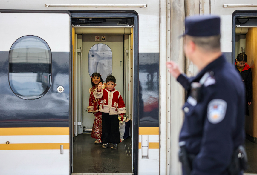 小朋友在和幫助自己乘車的鐵路公安民警揮手道別。