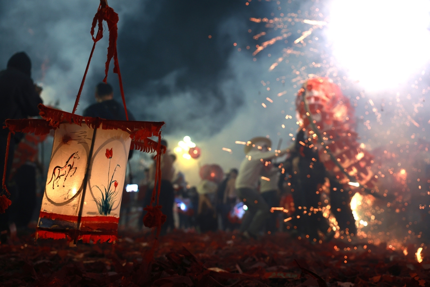 2月27日晚，贵州省黔东南苗族侗族自治州施秉县城街头，社区龙灯队的汉子们在炸响的鞭炮火光下舞动“亮龙”。 