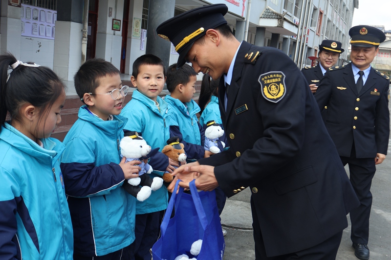 3 图为执法人员向小学生发放小礼品 。