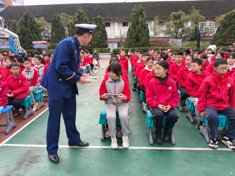 施秉县消防宣传员向施秉县第二小学学生发放《中小学生消防安全知识读本》。
