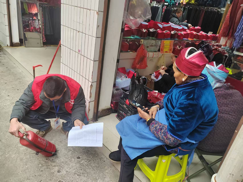 施秉縣城關鎮工作人員在商鋪認真查看滅火器有效期。