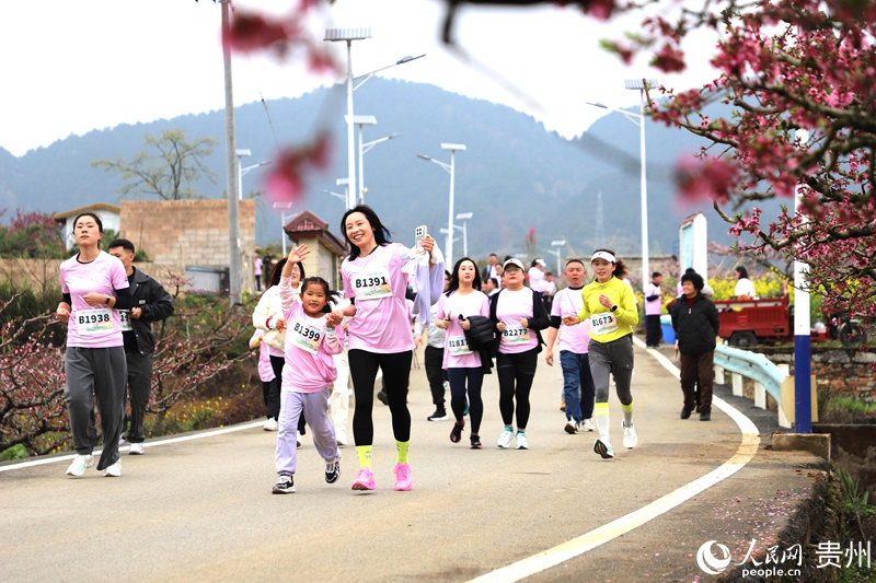 亲子选手在桃林赛道奔跑，感受乡野生机。人民网 龙章榆 摄