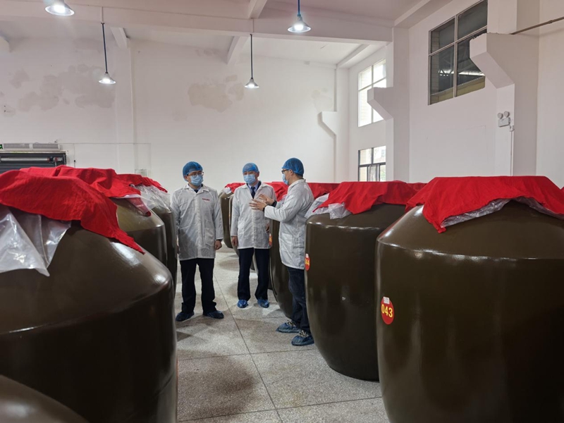 (图六 纳税人向税务干部讲解鱼酱酸装坛发酵原理)