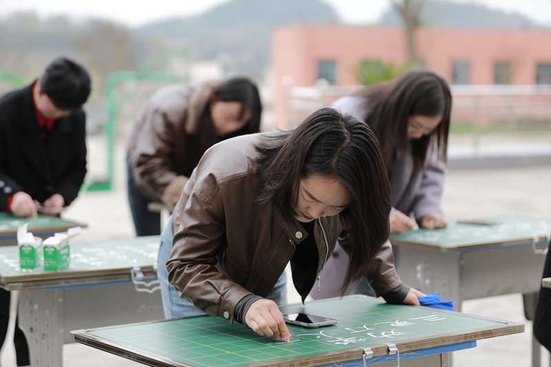 3月26日，黔西市林泉镇林泉小学的教师在操场上参加硬笔书法比赛。 