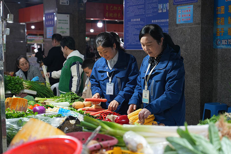 农贸市场工作人员对蔬菜进行抽查。