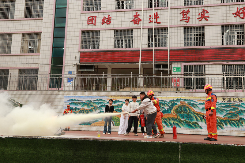 现场模拟起火场景，手把手教学生正确使用灭火器。王叶子摄