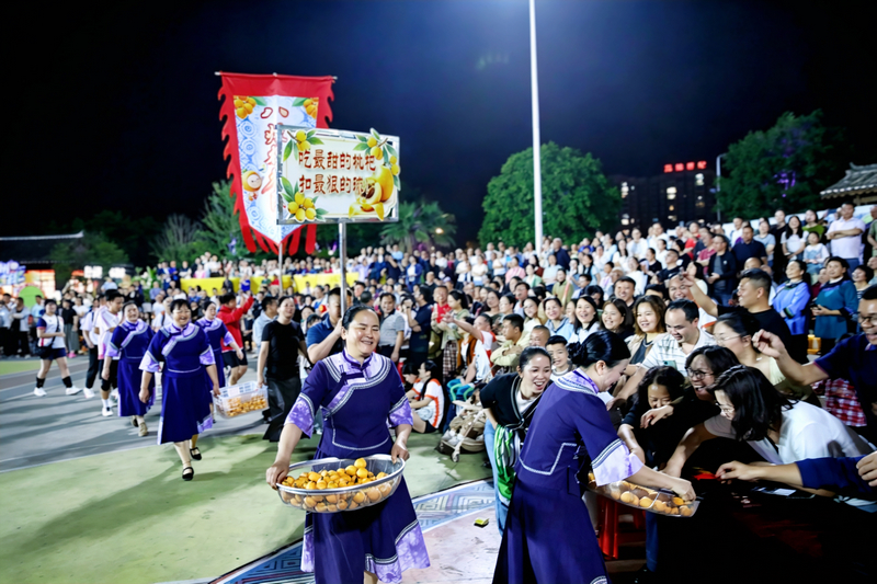 吃最甜的枇杷，扣最狠的球！4月19日晚，八烂村村民为现场观众送枇杷。吴治均摄
