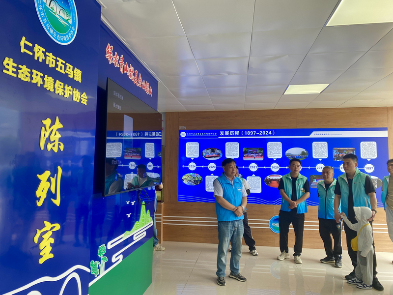 在仁怀市五马镇生态环境保护协会陈列室，志愿者们正在了解当地生态环境保护协会发展历程与当地生态环境的显著改善。