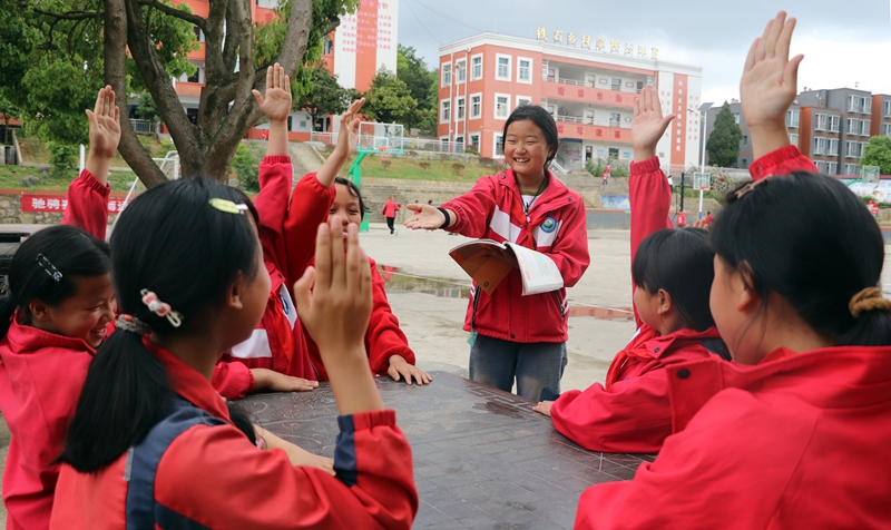 在黔西市铁石苗族彝族乡铁石小学，学生们正在校园树荫下流读书学习感想。