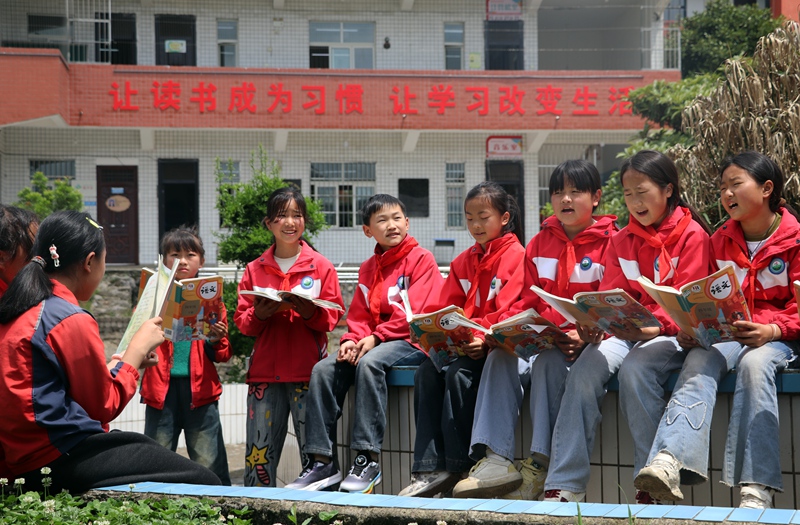 在黔西市铁石苗族彝族乡铁石小学，学生们正在校园树荫下流读书学习感想。