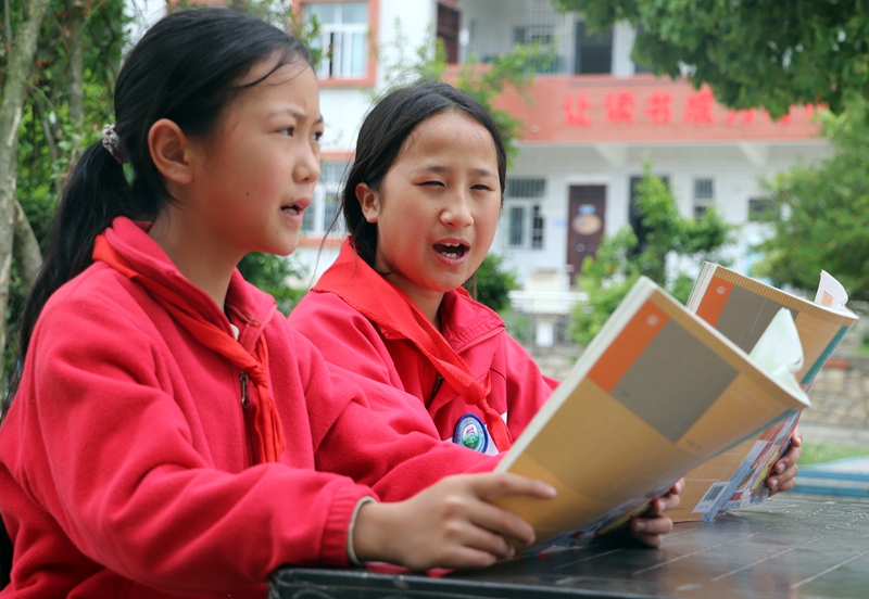 在黔西市铁石苗族彝族乡铁石小学，学生们正在校园树荫下流读书学习感想。