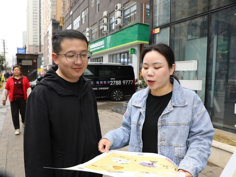 工作人员向居民宣传城市管理法规。杨洋摄