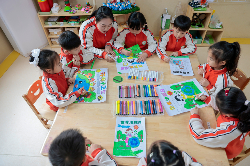 在贵州省黔东南苗族侗族自治州施秉县第四幼儿园，老师指导孩子们进行世界地球日主题绘画创作。